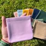 Hand holding pink PU leather coin bag with colorful options behind